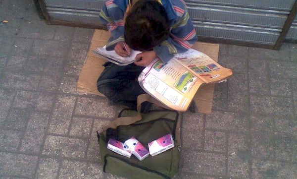 Παιδάκι πουλάει χαρτομάντιλα και διαβάζει (φωτογραφία)