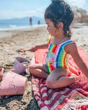 Η μικρή Μελίτα παίζει στην παραλία με ένα τέλειο ολόσωμο rainbow μαγιό με Μονόκερό.